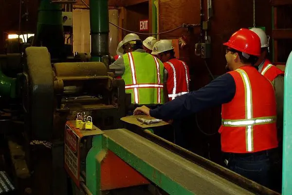 Workers in safety gear at factory machine